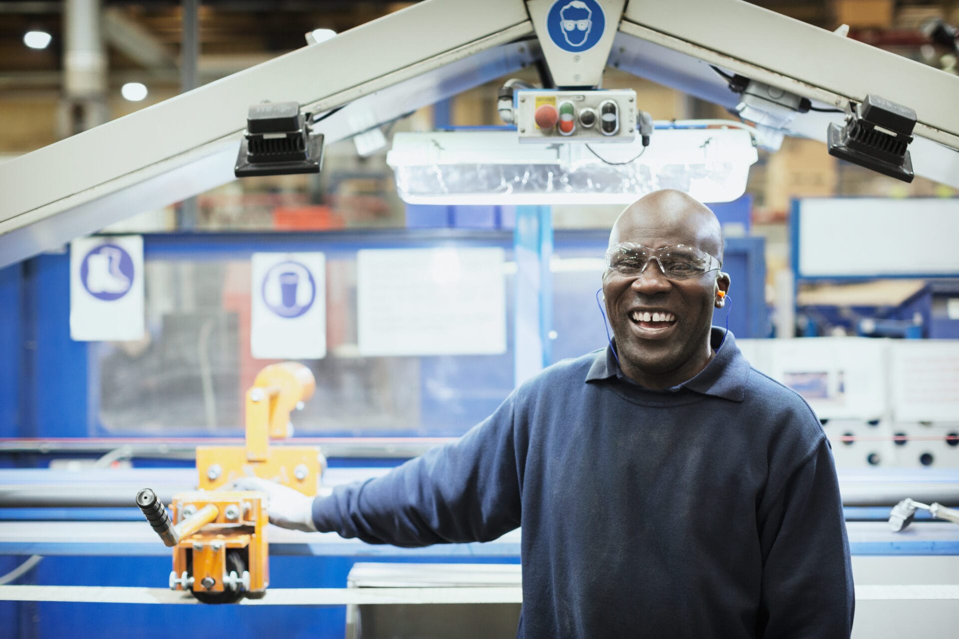man smiling while at work in manufacturing facility